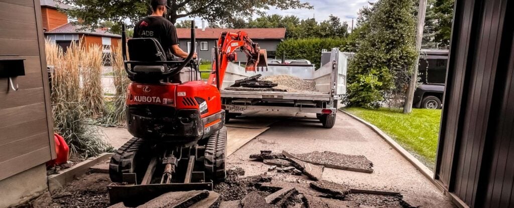 Mini-excavatrice retirant l’asphalte d’une entrée d’auto résidentielle.