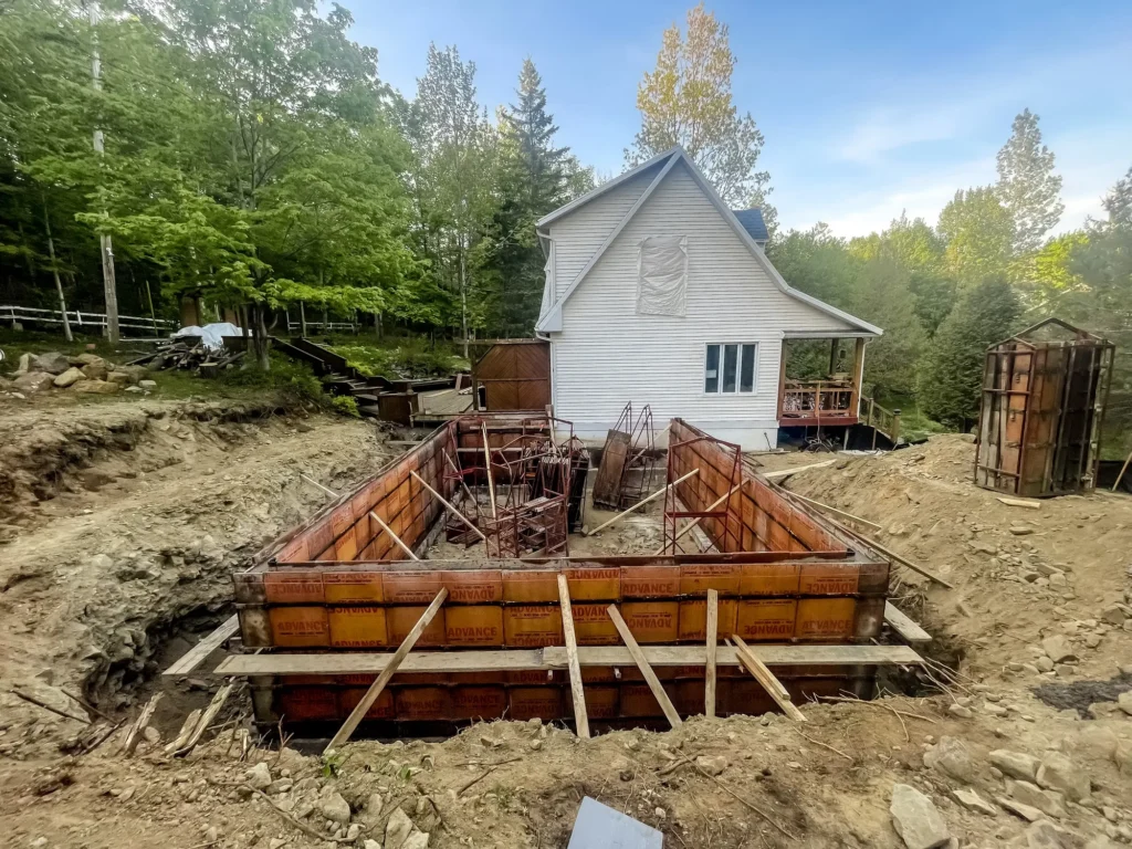Coffrage de fondation en béton pour agrandissement de maison sur chantier de construction en forêt