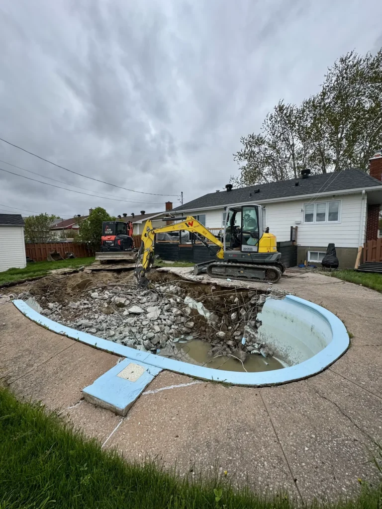 Démolition de piscine creusée avec excavatrice et pelle mécanique dans une cour arrière résidentielle