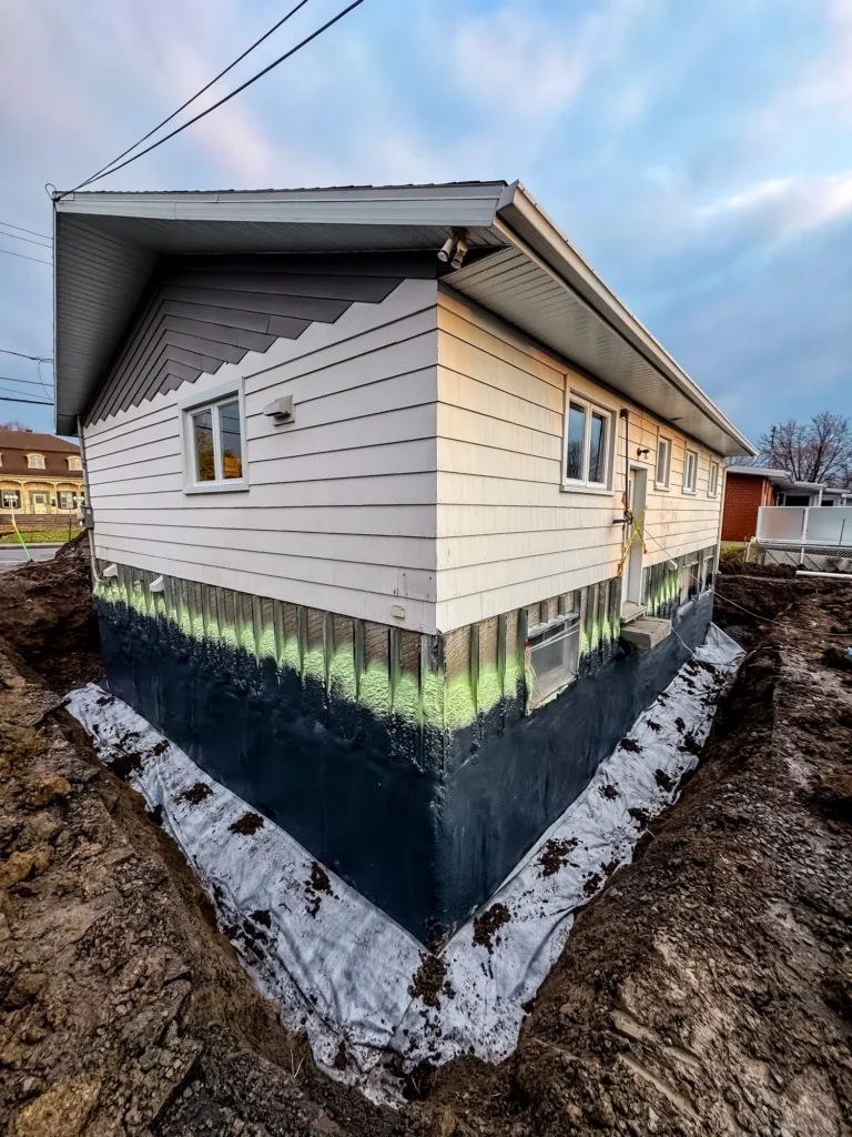 Fondation de maison excavée avec revêtement d'étanchéité noir et membrane de drainage pour imperméabilisation