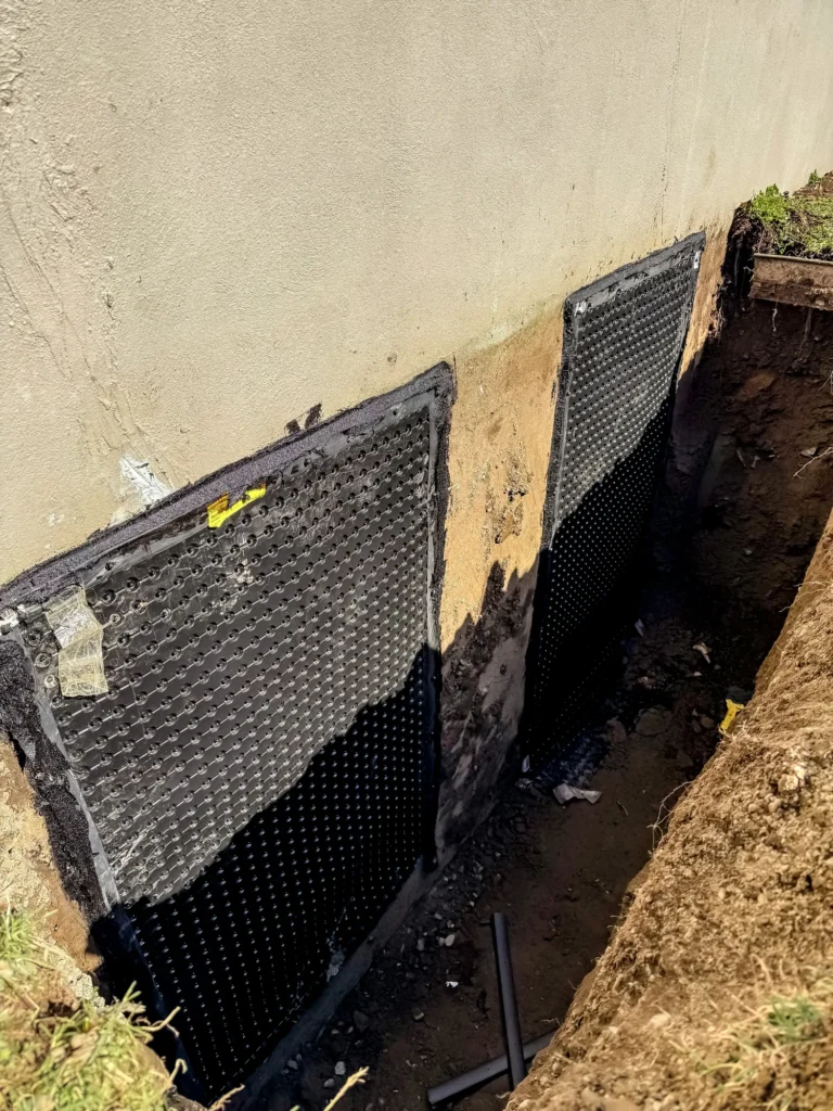 Membrane de drainage alvéolée installée sur mur de fondation dans une tranchée d'excavation pour impermeabilisation